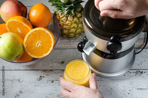 Man preparing fresh orange juice. Fruits in background