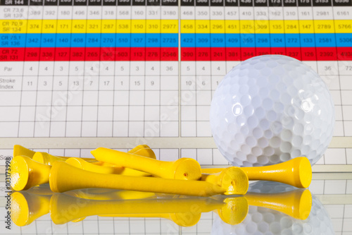 Golf score card and white ball on a glass desk