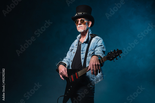 Heavy metal senior man with electric flying-v guitar in front of