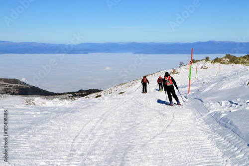 Three skiers descend from mountain peak, Cherni Vrah, Vitosha Mountain, Bulgaria
