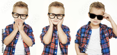 Funny child.fashionable little boy in glasses, jeans, white t-shirt and plaid shirt. concept of a fashion children which showed monkey motions: hear nothing, say nothing, see nothing