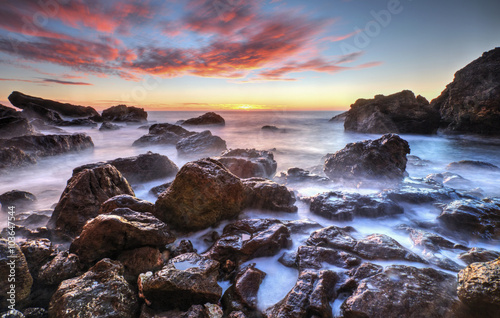 Beautiful sunrise on rocky shore and dramatic sky clouds