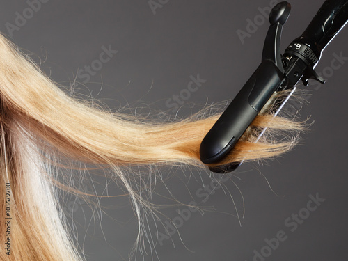 woman making hairstyle with hair iron