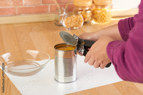 woman opening a can of corn with can opener