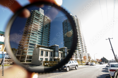 Polarizing filter held in front of a camera lens showing difference of polarized and unpolarized street scene.