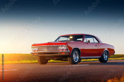 Retro red car stay on asphalt road at sunset