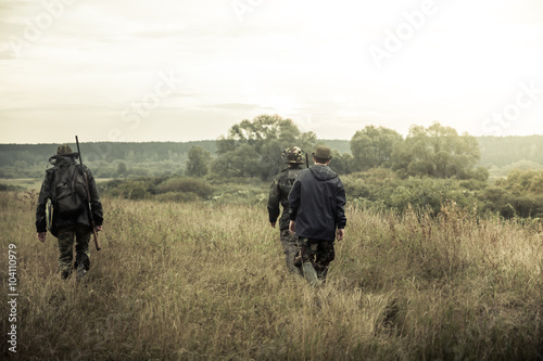 group of people going up in the early morning in a rural field through the tall grass during hunting