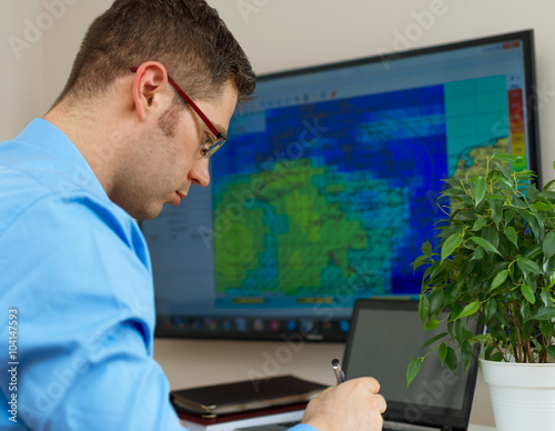 Handsome male meteorologist in glasses on his workplace.