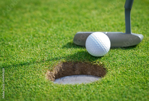 Close-up of golf hole with putter and ball