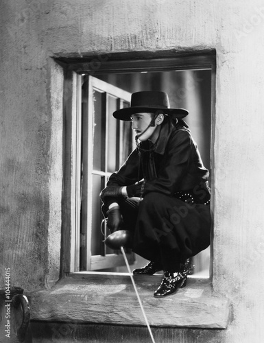 Woman as Zorro crouching in a window 