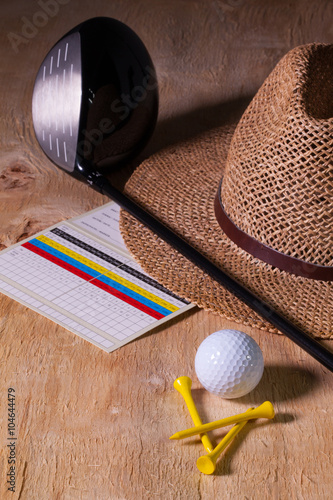Siesta - straw hat and golf driver on a wooden desk