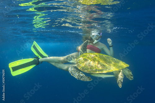 Young woman swims with sea turtle