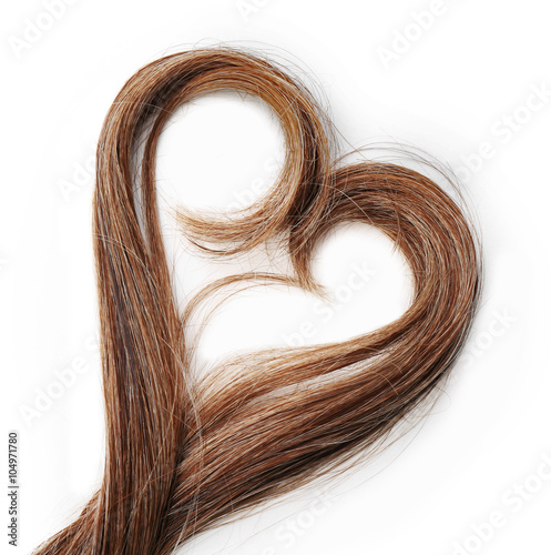 Strands of brown hair in shape of heart, isolated on white