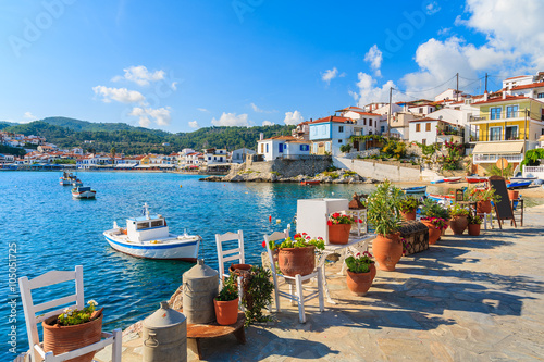 Flower pots on and view of fishing boats anchoring in Kokkari bay, Samos island, Greece