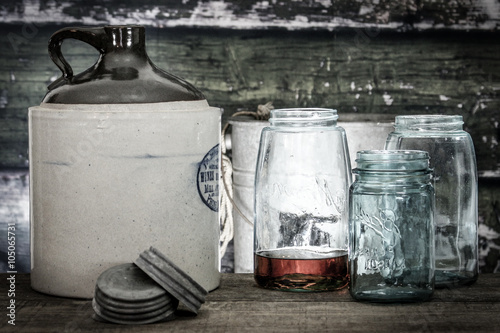 Vintage crock jug with mason jars, one with bourbon or whiskey within