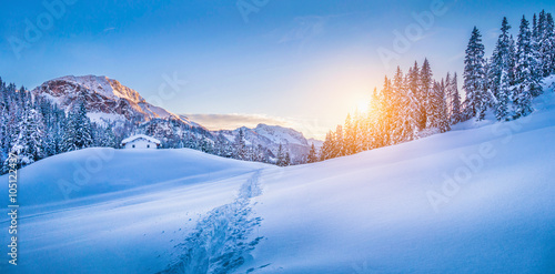 Winter wonderland in the Alps with mountain chalet at sunset
