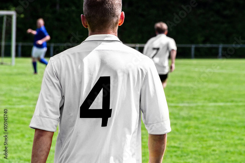 Fußballspieler auf dem Spielfeld im weißen Trikot von hinten