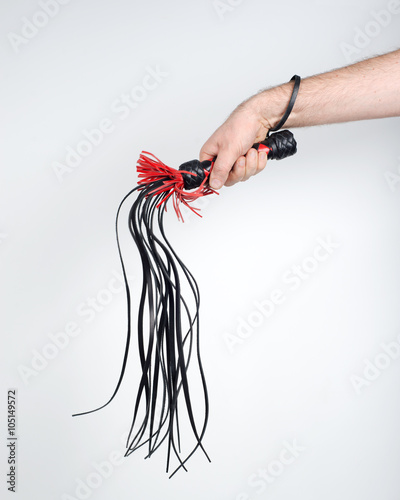 Man's hand holds a whip (flogger).