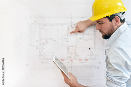 Bauingenieur mit Tablet vor technischer Zeichnung beim Hausbau // engineer with Tablet and technical drawing in house construction