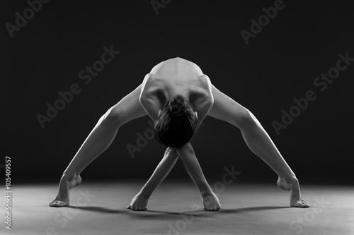 Nude yoga. Beautiful sexy body of young woman on black background