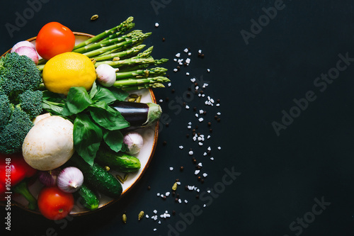 Heap of vegetables on ceramic plate on black background