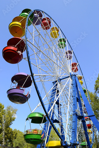 Ferris wheel, bottom view. The park named after Gagarin, Novokuznetsk, Kemerovo region, Russia. Multi-colored booths against the blue sky.