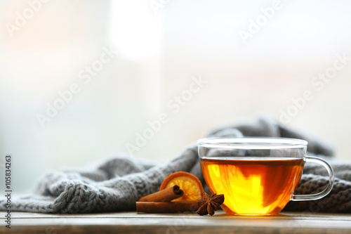 Glass cup of tea with grey plaid on wooden table