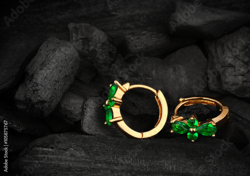 jewelry earrings witht gem emerald on dark coal background, soft