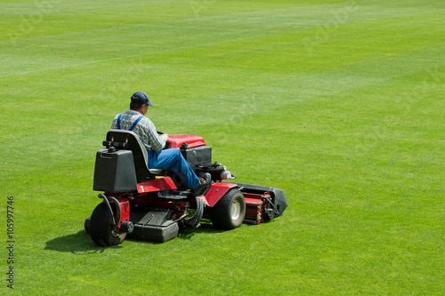  A man mowing the grass on a football stadium.