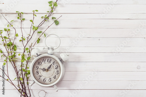 Background with white alarm clock and spring branch on white pai