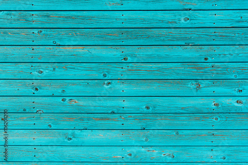 Section of textured turquoise wood panelling from a seaside beach hut. Could be used as a background to illustrate beach and summer holiday themes. 