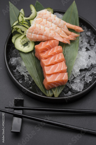 Salmon sashimi on a bamboo list and ice over black background