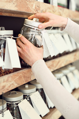 Kobieta wybiera rodzaj herbaty podczas zakupów w sklepie herbacianym