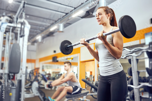 Strong woman weightlifting at the gym looking happy and working on her biceps