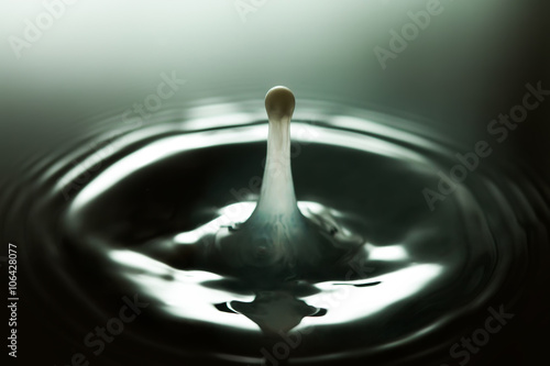 Milk splash close-up. White bubble drop with rings waves in darkness. Transparency concept. macro view, soft focus, shallow depth of field. copy space