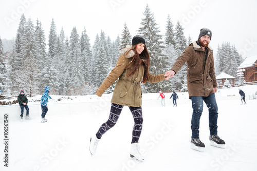 Portrait of a smiling couple ice skating outdoors