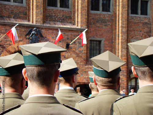 Obchody majowe z okazji rocznicy uchwalenia Konstytucji 3 Maja. Żołnierze wojska polskiego stoją na toruńskim rynku, a w tle polskie, biało czerwone flagi.