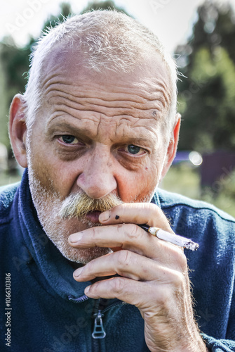 starszy mężczyzna palący papierosa