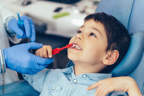 Child at dentist's office, learning about tooth brushing techniques 