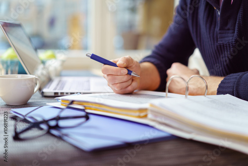 mann arbeitet mit laptop und unterlagen