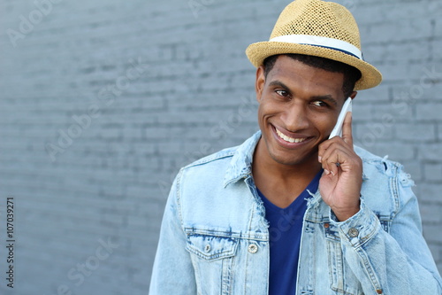 Young black man smiling and talking on mobile phone outside with copy space on the right 