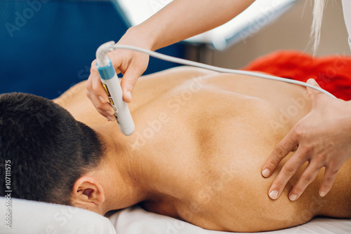 Laser treatment in physical therapy. Therapist using low intensity laser beam to treat patient