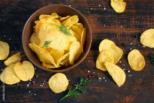 Potato chips with greens in a bowl, top view