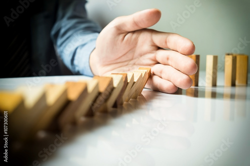 businessman hand stop dominoes continuous toppled or risk with c