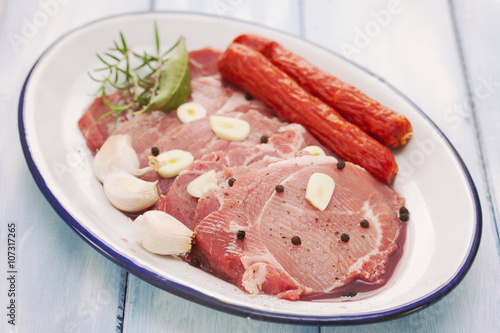 pork with black pepper, smoked sausages and garlic on dish on blue wooden background