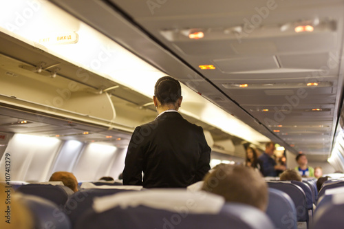 Interior of airplane with passengers and stewardess walking the aisle