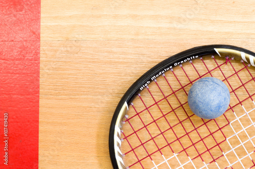 Close up of a squash racket and ball on the wooden background