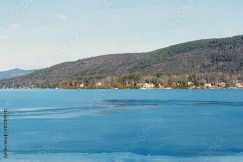 Color DSLR stock image of a frozen Lake George, with lake houses on the shore and Adirondack Mountains in background. Horizontal with copy space for text 
