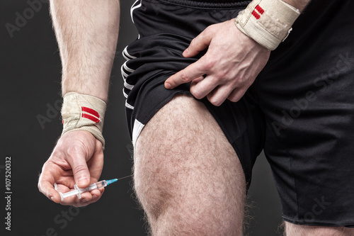 Closeup of a man injecting himself with steroids.