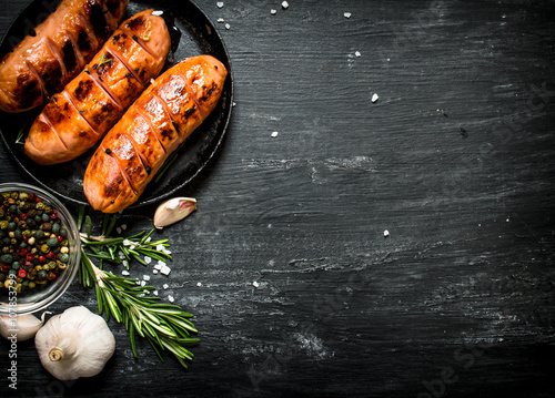 Fried sausages with garlic and herbs in a pan.
